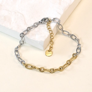 Macro detail of two-tone stainless steel chain bracelet with lobster clasp and tag