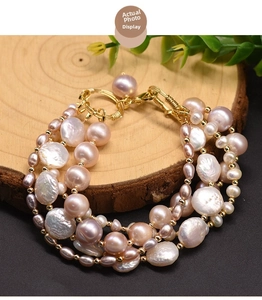 Detail of multi-layer baroque freshwater pearl bracelet with golden clasp on wood
