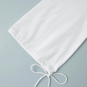 Detail of white cotton dress showing elastic cuff and elegant bow tie-up decoration