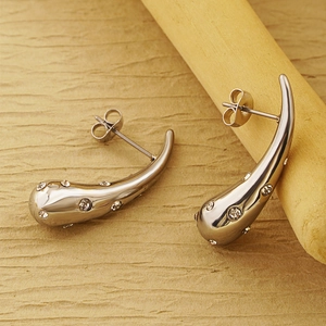 Macro shot of silver teardrop earrings with crystals on a wooden decorative stand