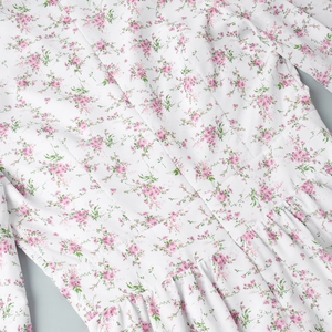 Detail view of pink floral print on white chiffon dress with high waist pleats and ruffles