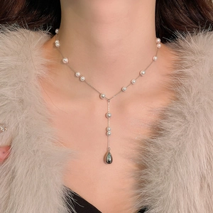 Détail d'un élégant collier en Y argenté avec perles et pendentif goutte sur le cou