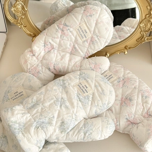 Close-up of quilted floral cotton gloves with diamond stitching and woven label detail