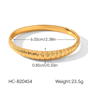 Detail shot of golden titanium steel bangle showing dimensions and croissant texture
