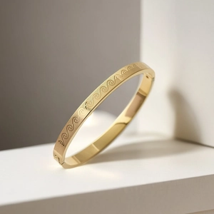 Detailed view of golden titanium steel bangle with etched continuous wave patterns