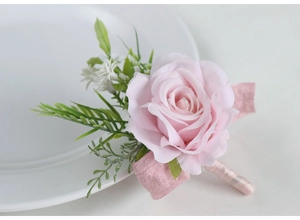 Macro shot of handmade pink silk rose boutonniere with green fern leaves and ribbon