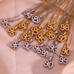 Macro shot of 18K gold and silver year number pendants with micro-pave crystals