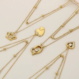 Detailed view of gold beaded satellite chains with rhinestone heart and crown pendants