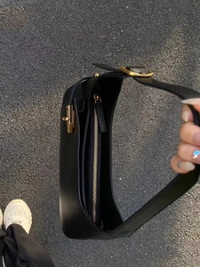 Detailed close-up of a black leather hobo bag with a decorative gold buckle and top zipper