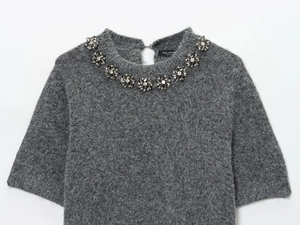 Dettaglio del maglione grigio a maniche corte con decorazione floreale in cristallo sul collo