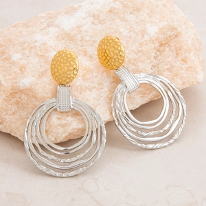 Detailed shot of two-tone gold and silver textured drop earrings on natural stone