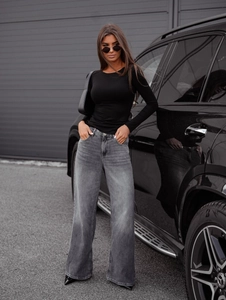 Detail of slim fit black long sleeve top and high waist wide leg grey jeans on a model