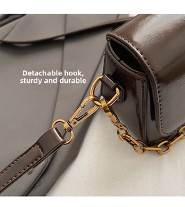 Macro detail of high-quality gold hardware and detachable hook on dark brown leather bag