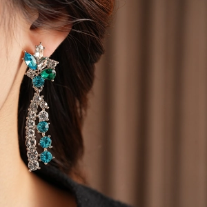 Detailed view of silver crystal drop earrings with blue gems worn by a model