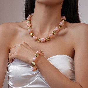 Detail of chunky pink marble acrylic beads and golden beads on model jewelry set