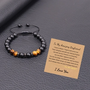 Tiger eye and matte stone beaded bracelet for men with gift card on leather background