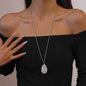 Teardrop white stone pendant long necklace on silver chain worn by a model