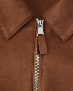 Détail d'une veste en daim marron avec fermeture éclair argentée et col de haute qualité