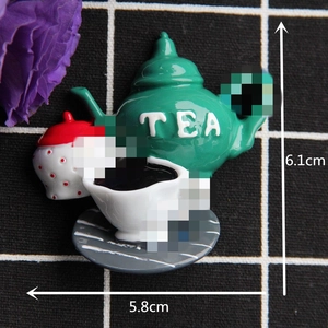 Detailed top view of miniature tea set accessories featuring a green TEA teapot and cup