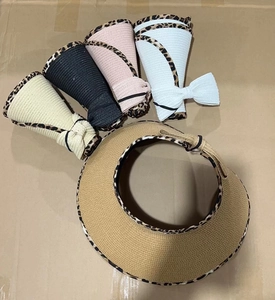 Detail of straw sun visors with leopard print trim and bow decoration in various colors