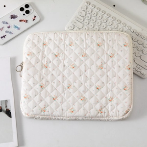 Detail of floral quilted cotton laptop sleeve with soft texture and metal zipper closure