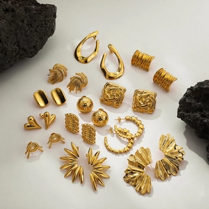 Detailed collection of ten varied gold earrings with textures on neutral background