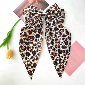 Detail of large leopard print bow hair clip with streamers on a clean background