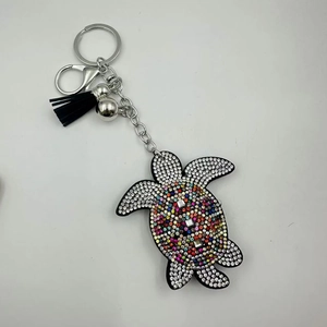 Macro detail of turtle keychain with colorful rhinestones and black fabric tassel