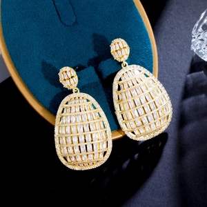 Luxury gold hollow oval drop earrings with shimmering pavé zircon on blue velvet