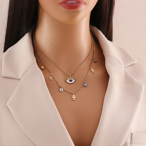 Detail of double-layered gold necklace with enamel evil eye and Hamsa hand charms