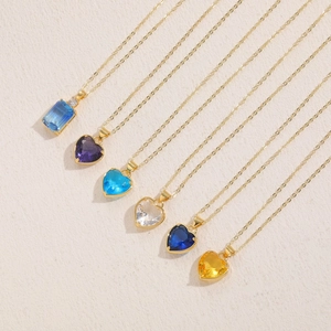 Detail of multiple gold necklaces with colorful heart and rectangle glass pendants