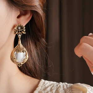 Gros plan de boucles d'oreilles fleurs vintage dorées avec perles blanches et strass
