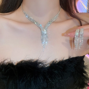 Set di collana e orecchini a goccia con strass argentati indossati da una modella elegante
