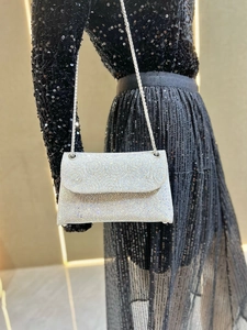 Detail of silver rhinestone shoulder bag with chain strap shown on a model