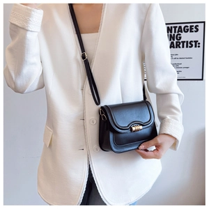 Detail of black leather crossbody bag featuring gold twist lock and adjustable strap