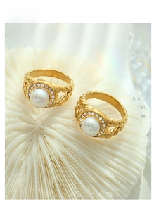 Close-up of gold titanium steel ring with fresh water pearl and zircon on white coral
