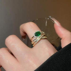 Detail of three-layer gold ring featuring an oval green gem and pavé zircon accents