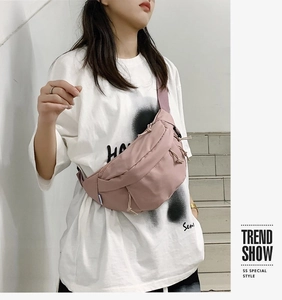 Pink nylon crossbody bag worn by a model in a casual street style setting