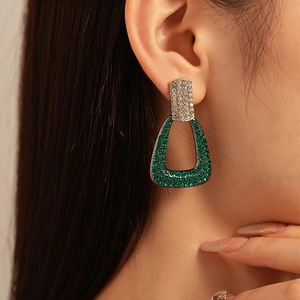 Close-up of geometric earrings with green zircon and micro-pave crystals on model