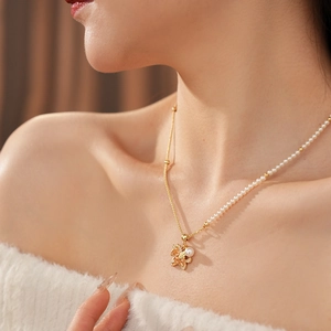Detail of fox pendant necklace with white pearl and gold chain on elegant model