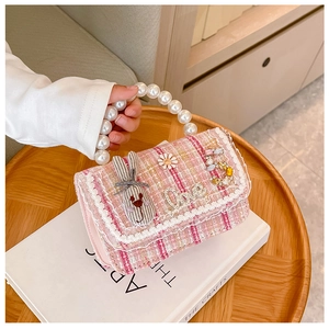 Detail of pink tweed girl's handbag with large pearl handle and cute fabric bunny decor