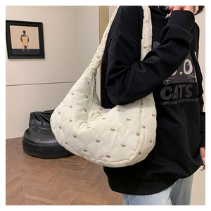 Detail der cremefarbenen Stepptasche mit brauner Schleifenstickerei und Puffy-Struktur