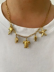 Détail du collier plaqué or 18K avec pendentifs étoile de mer et tortue sur un t-shirt blanc