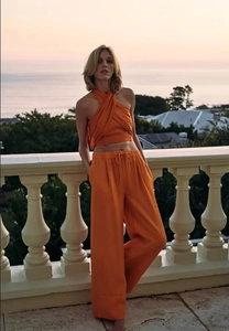Detailaufnahme von orangefarbenem Halter-Crop-Top und weiter Hose in Leinenoptik
