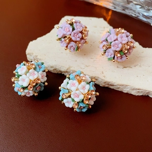 Makroaufnahme von Blumen-Ohrsteckern mit Kristallen in Pink und Blau auf Stein
