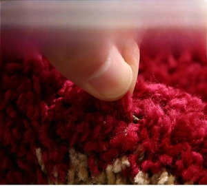 Macro shot showing durable fibers and anti-shedding lock technology on deep red rug