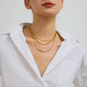 Detail of triple layered gold titanium steel necklaces featuring paperclip and snake chains
