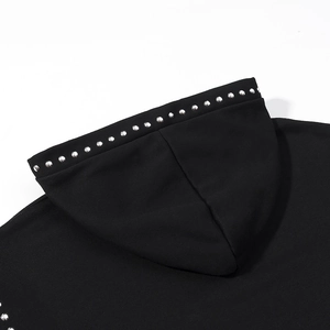 Detailed close-up of silver studs on a black hooded sweatshirt with soft fabric texture
