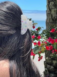 Dettaglio del fermaglio a farfalla con strass colorati sui capelli in spiaggia