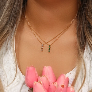 Detail of two 18K gold plated necklaces featuring three pear-shaped green and white zircons